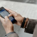 Tangan memegang smartphone menampilkan aplikasi GPS untuk melacak lokasi